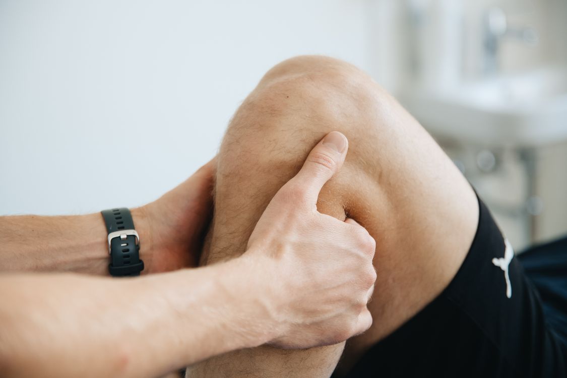 Physiotherapist applying therapeutic treatment to patient knee joint demonstrating topical pain relief application technique