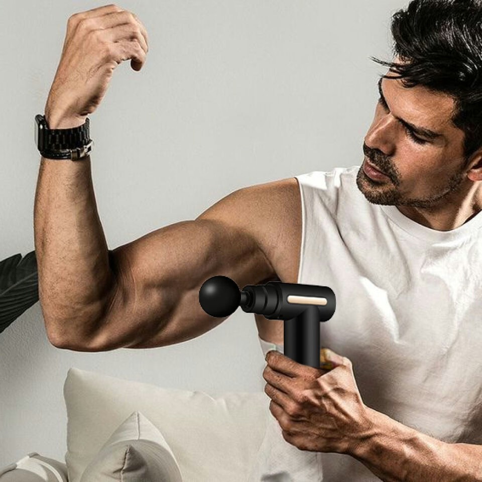 Man applying TheraOne Pro percussion massage gun to bicep and upper arm muscle for post-workout soreness relief