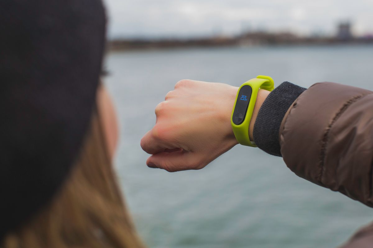 Person checking a smartwatch outdoors during a walk, tracking resting heart rate and activity trends