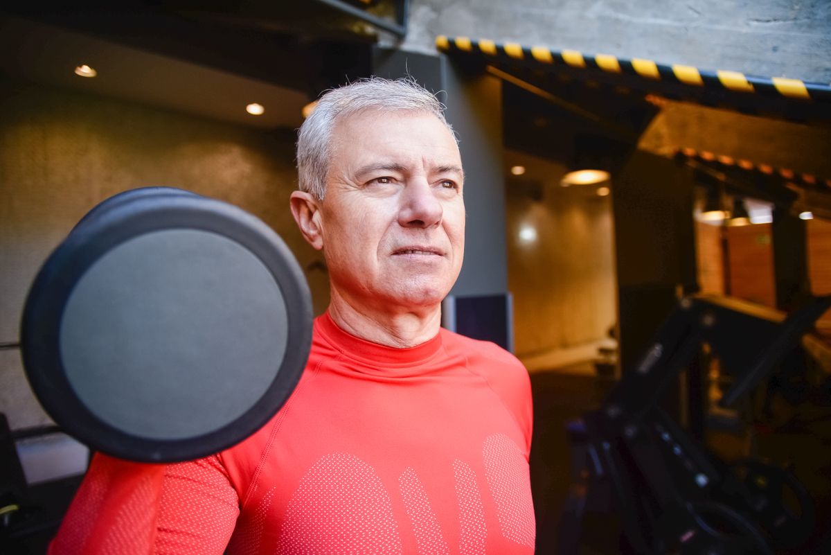 senior man doing a barbell workout at the gym to build strength after 40