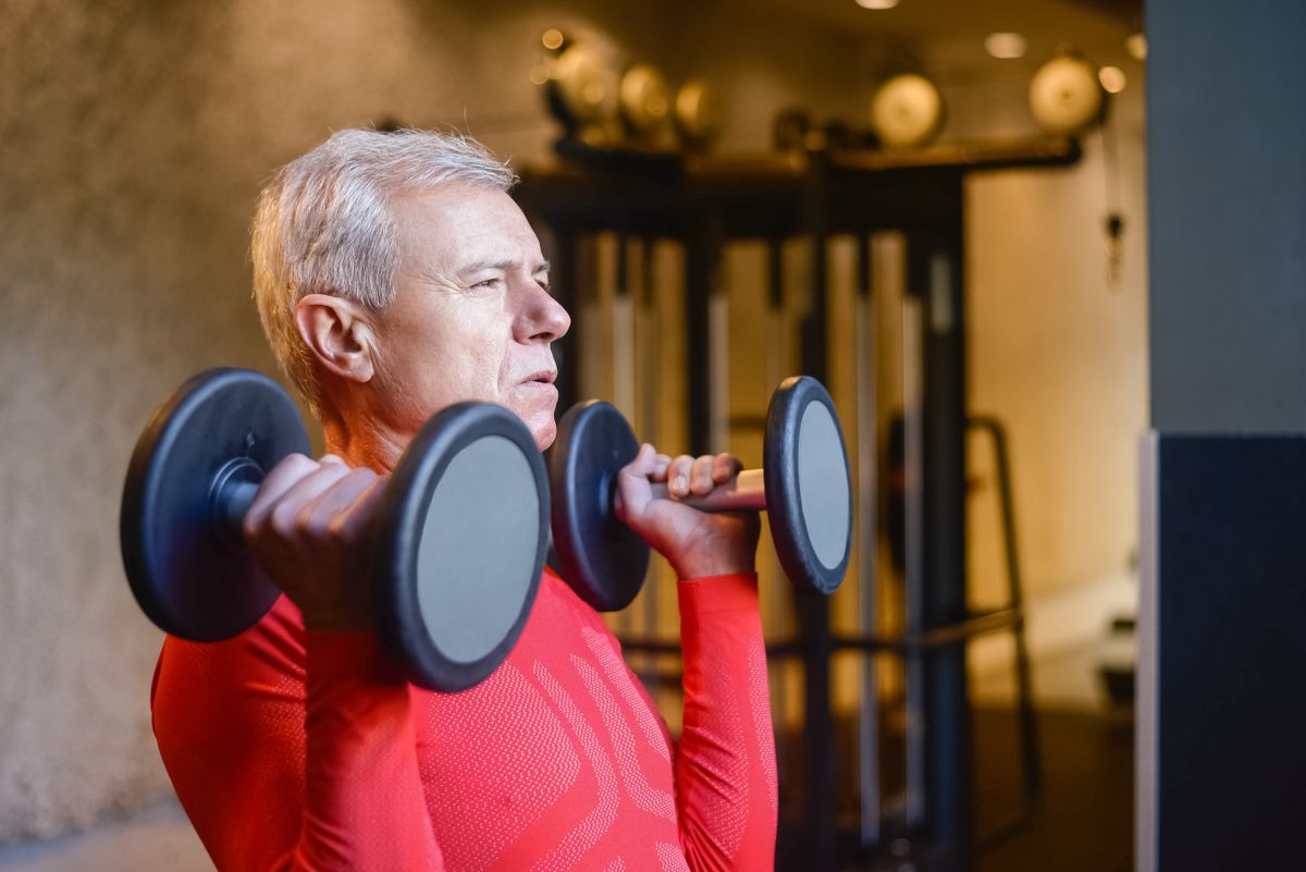 older man lifting dumbbells during a strength training session, illustrating creatine after 40 for muscle building