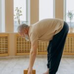 senior man practicing gentle yoga stretch on mat indoors showing yoga for joint pain after 40