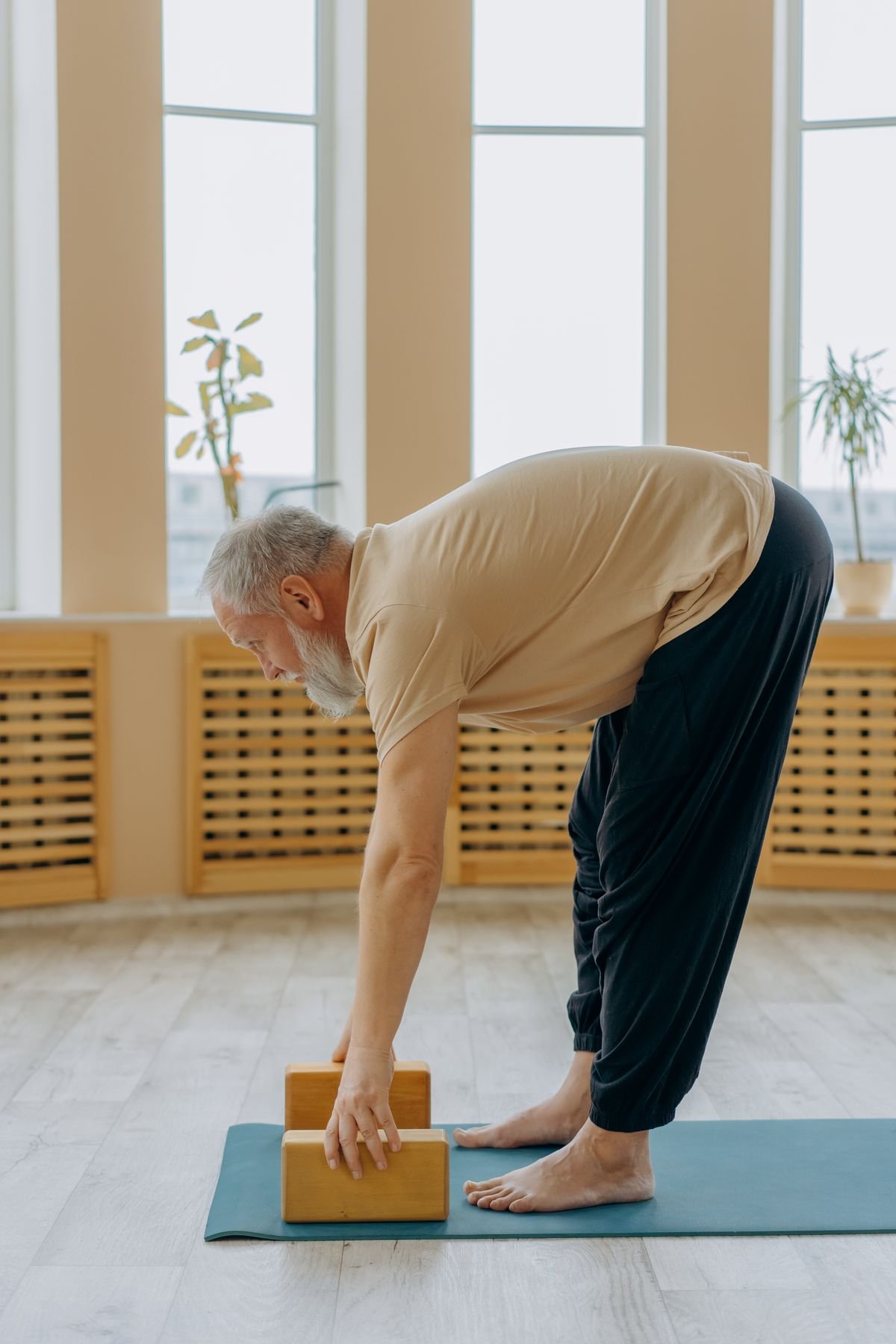senior man practicing gentle yoga stretch on mat indoors showing yoga for joint pain after 40