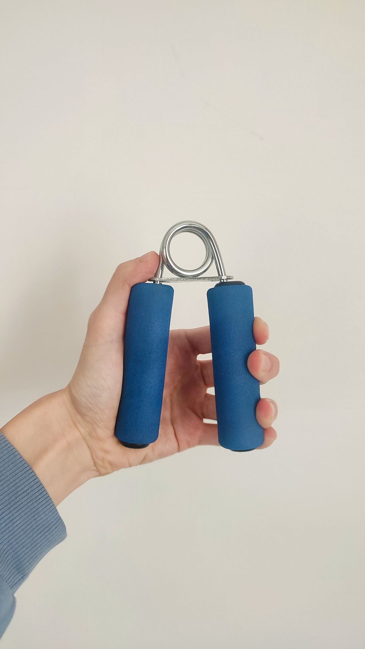 Close-up of a hand gripping a hand exercise tool used to test and build grip strength