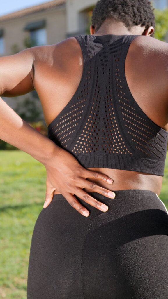 Woman holding her hip and lower back outdoors, illustrating where hip bursitis and hip arthritis pain typically differ