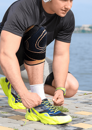 person wearing KneeHero knee compression sleeve outdoors while tying running shoes, showing fit during daily activity
