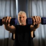 Older man doing strength training with dumbbells to prevent sarcopenia and muscle loss after 40