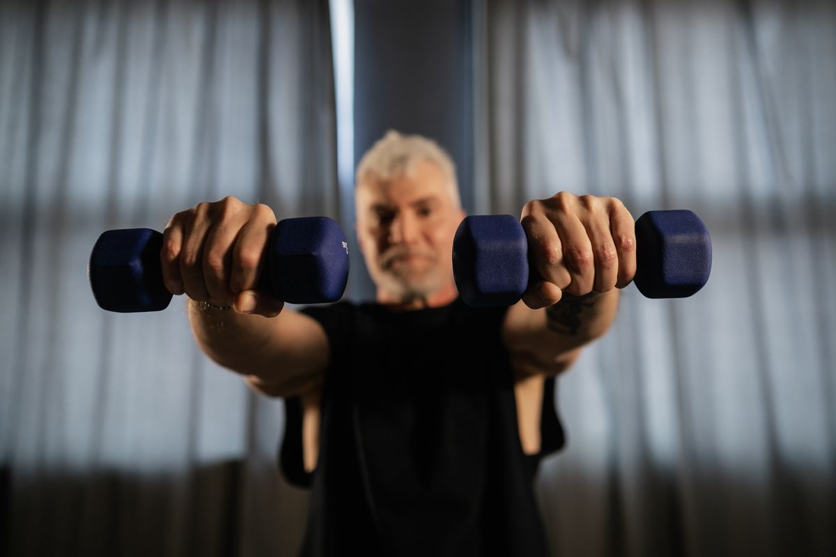 Older man doing strength training with dumbbells to prevent sarcopenia and muscle loss after 40