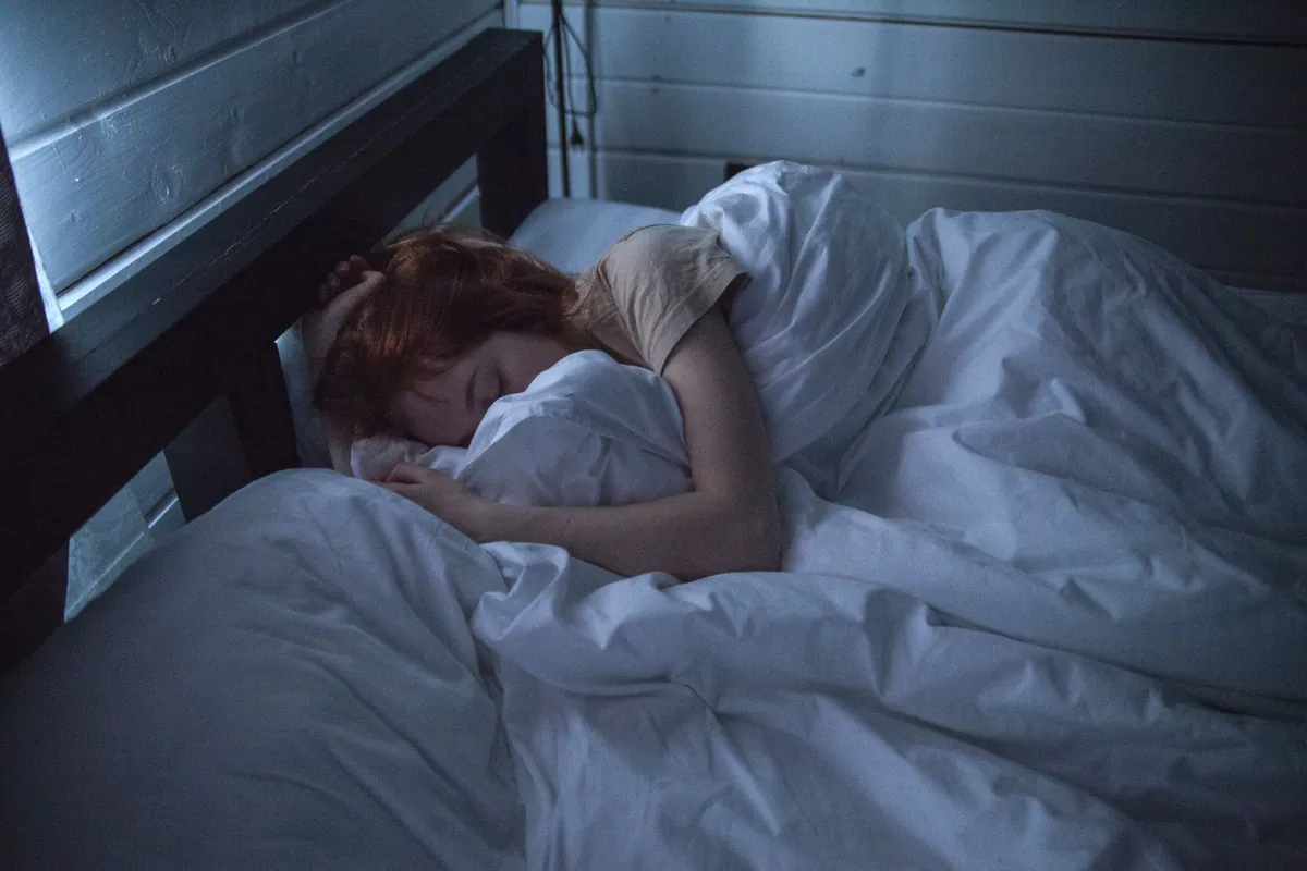 Person sleeping on their side in bed, the position a butterfly pillow is designed to support with its raised side wings