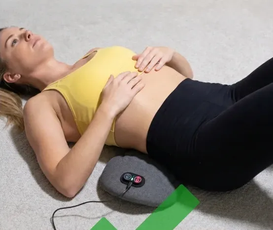 Woman lying on a carpeted floor with the Back Restore plugged in under her lower back