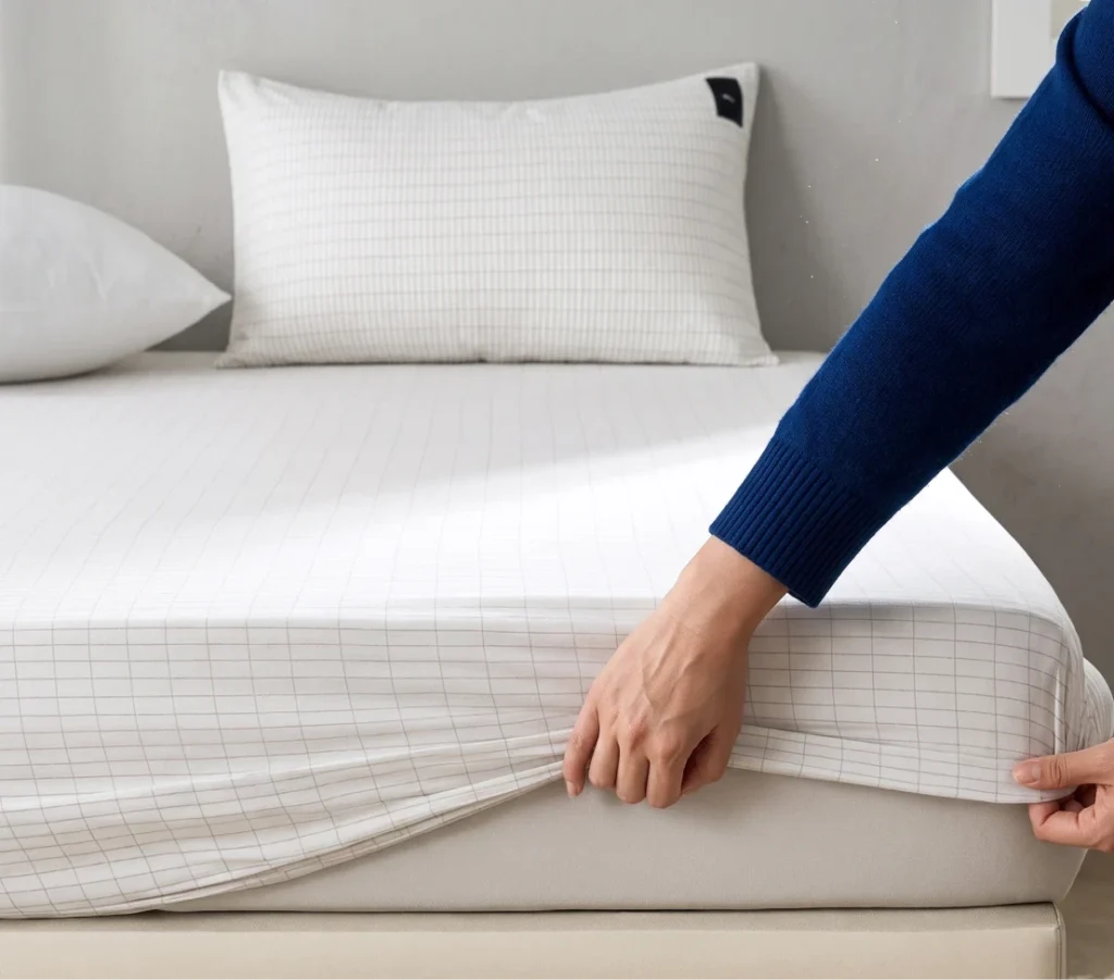 Velin grounding bed sheets fitted on a mattress, showing the silver thread grid woven into the white organic cotton