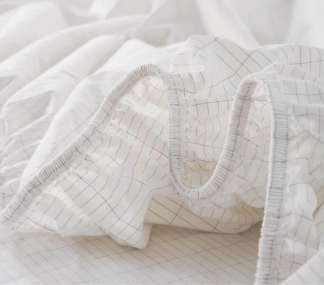 Close-up of Velin grounding sheets showing the elastic fitted edge and the silver thread grid in the organic cotton fabric